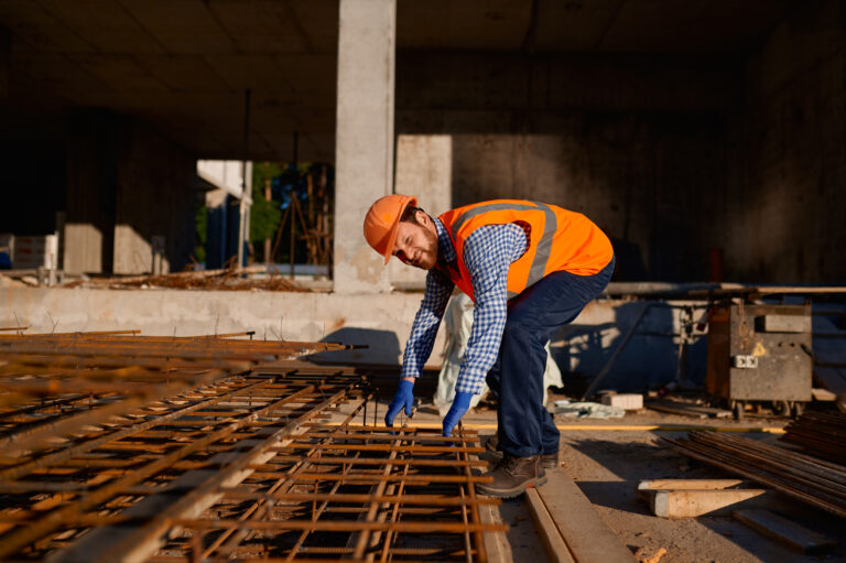 Construction worker taking metal grid reinforcing armature